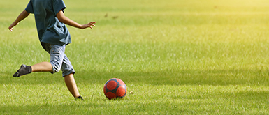 子どもがサッカーでボールを蹴る瞬間の写真